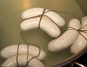 zwei zusammenhängende Würste mit der Prüfnummer verknotet und in einem Top aus Salzwasser auf 70 Grad Celsius erhitzt